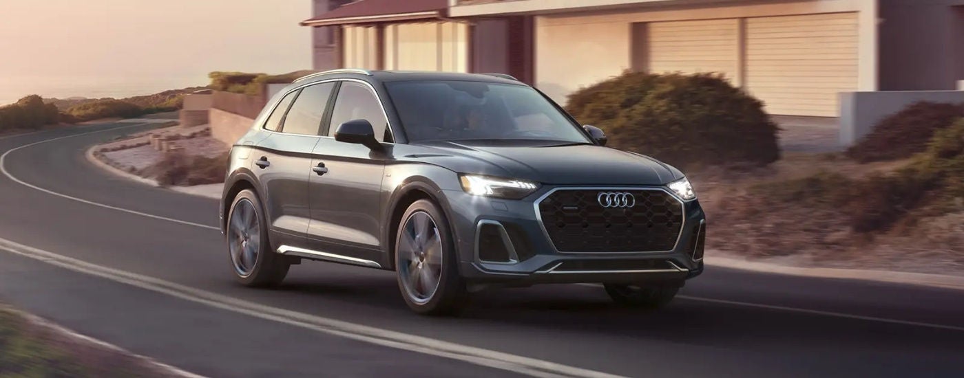 Grey 2023 Audi Q5 driving on a winding road.
